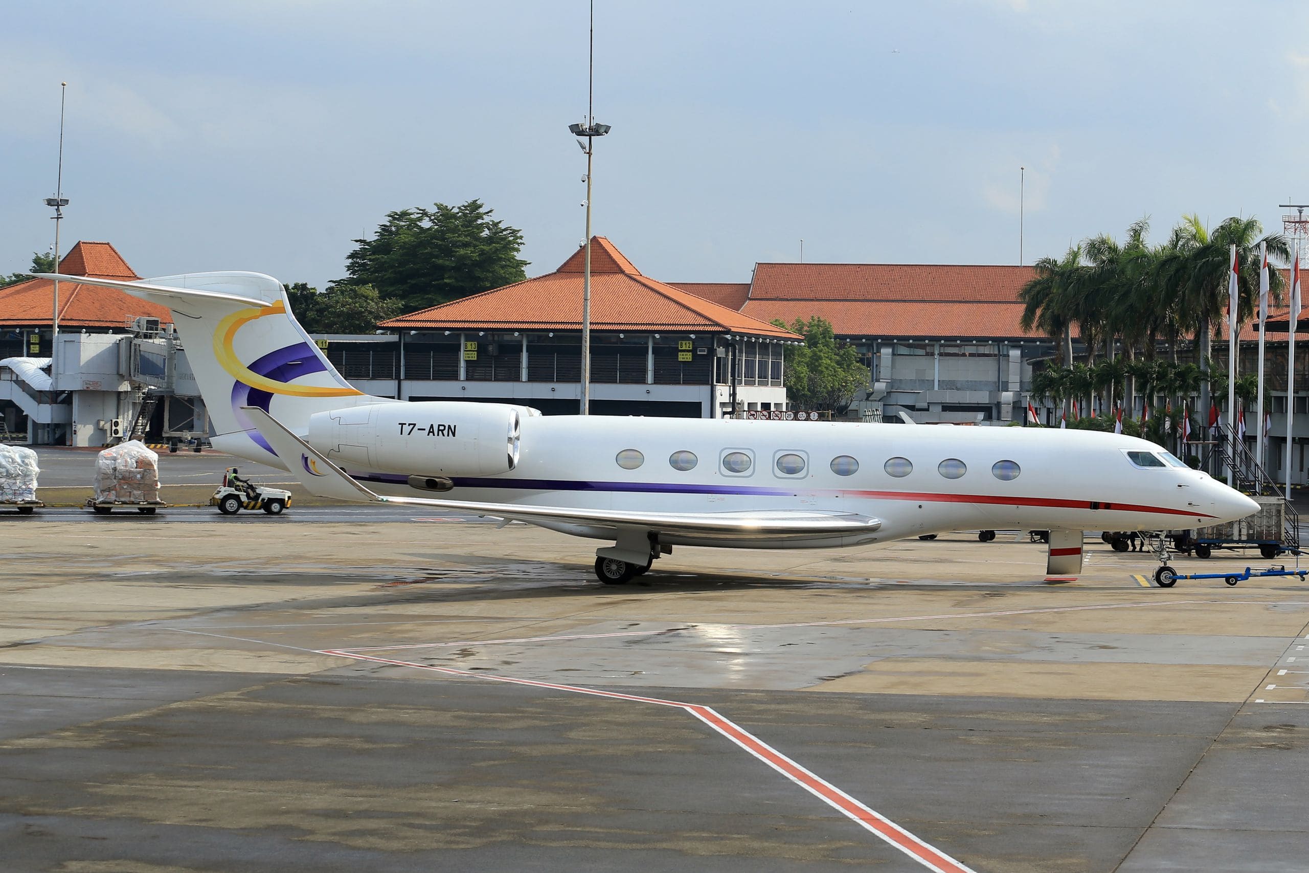 Black private jet on the tarmac at sunset with a red carpet leading to its open stairway
