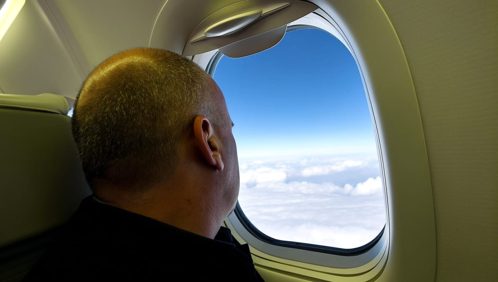 A passenger looking out over the clouds from a private jet cabin