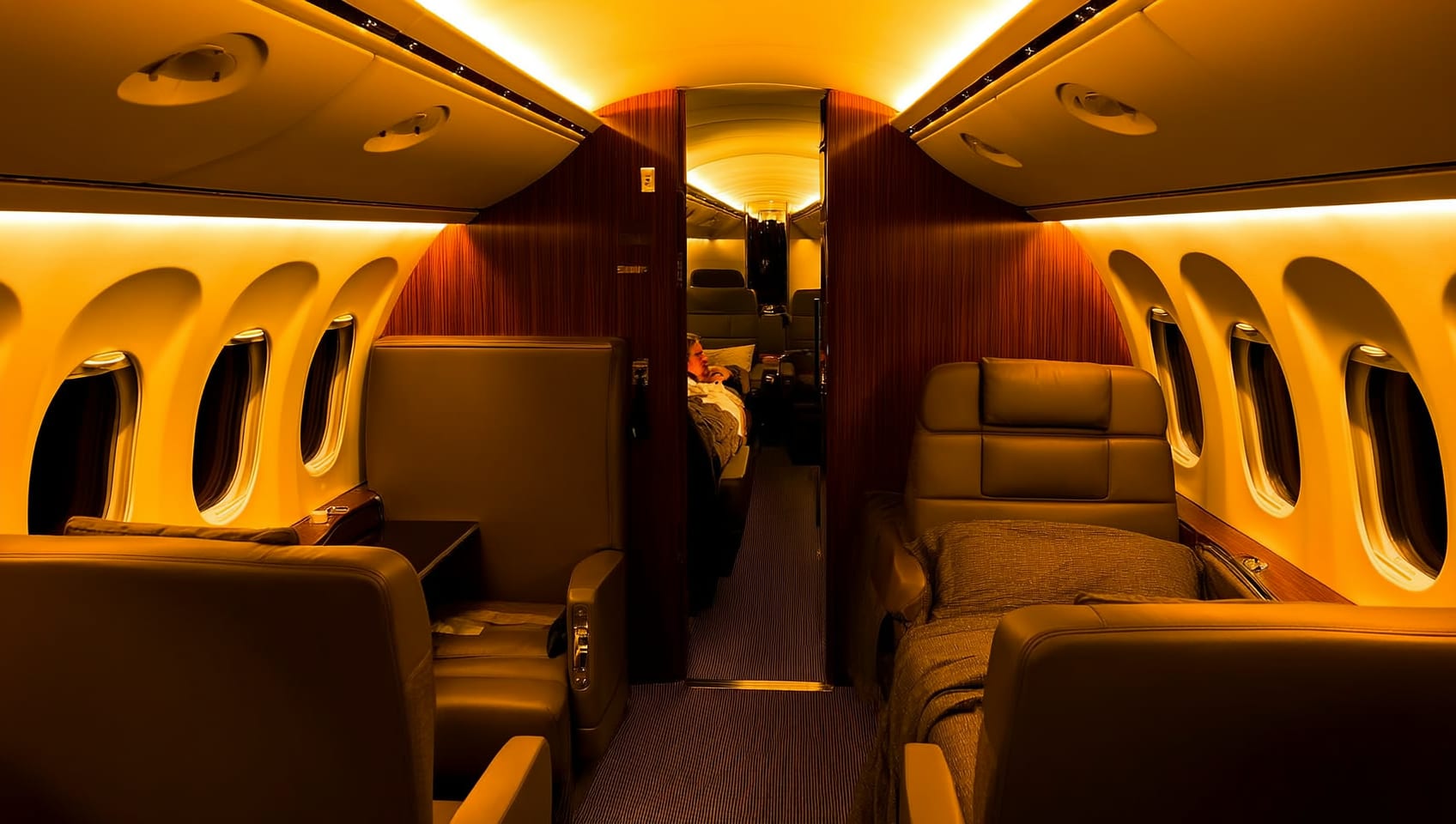 An ultra long range private jet cabin interior at night with lounge and sleeping areas visible